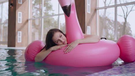 enjoy-calmness-in-spa-center-woman-is-lying-on-inflatable-flamingo-and-floating-in-swimming-pool